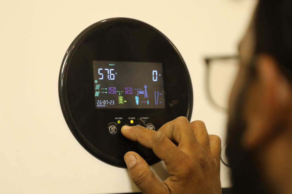 A solar energy system installation technician adjusts the system's battery settings at a home, in Omdurman, on the outskirts of Khartoum, Sudan, July 23, 2026. (AP Photo/Mohnd Blal)