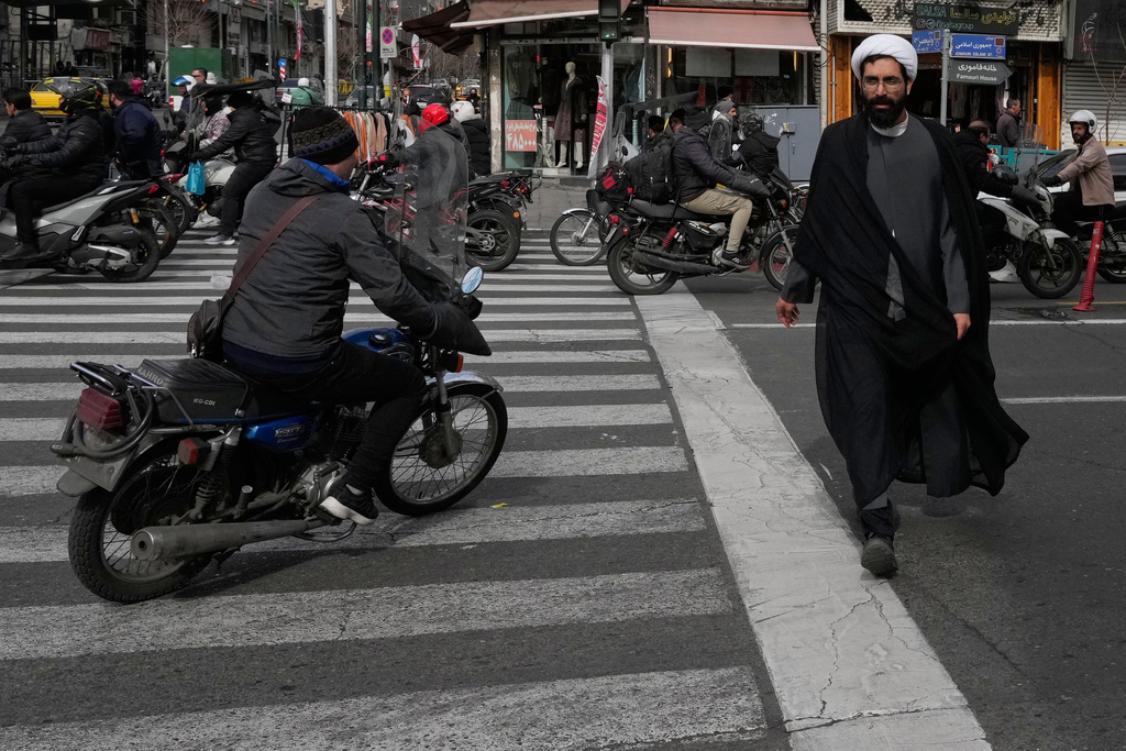 A cleric crosses an intersection in downtown Tehran, Iran, Monday, Feb. 9, 2026. (AP Photo/Vahid Salemi)