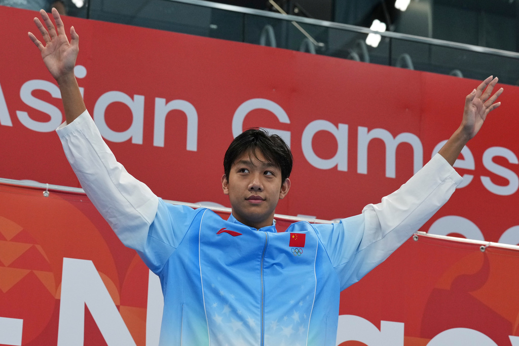Gold medalist Zhang Zhanshuo of China reacts as he stands on the podium to receive his gold medal following the men's 400m freestyle swimming final at the Asian Games in Tokyo, Japan, Friday, Sept. 25, 2026. (AP Photo/Hiro Komae)