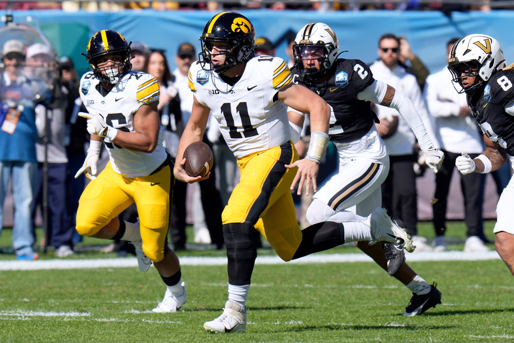 Iowa quarterback Mark Gronowski (11) runs past Vanderbilt safety Randon Fontenette (2) during the first half of the ReliaQuest Bowl NCAA college football game Wednesday, Dec. 31, 2025, in Tampa, Fla. (AP Photo/Chris O'Meara)