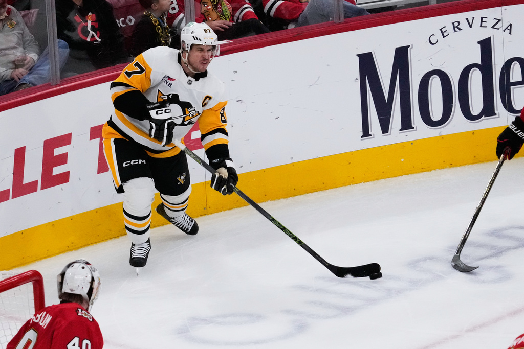 Pittsburgh Penguins center Sidney Crosby, top, passes the puck during the second period of an NHL hockey game against the Chicago Blackhawks in Chicago, Sunday, Dec. 28, 2025. (AP Photo/Nam Y. Huh)