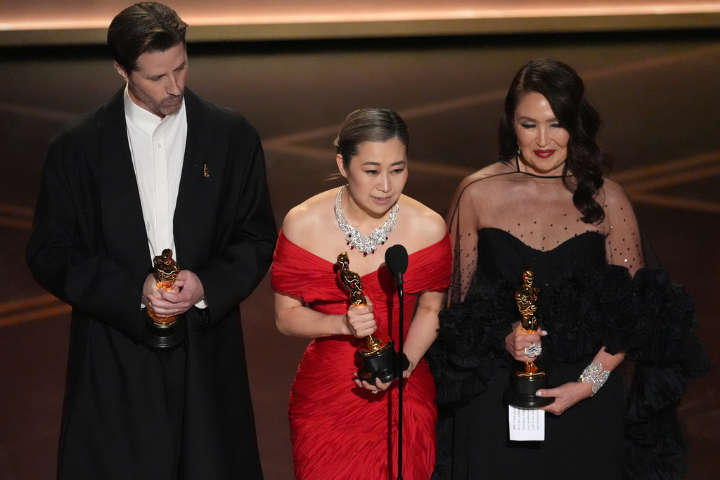 Chris Appelhans, from left, Maggie Kang, and Michelle L.M. Wong accept the award for animated feature film for "K-pop Demon Hunters" during the Oscars on Sunday, March 15, 2026, at the Dolby Theatre in Los Angeles. (AP Photo/Chris Pizzello)