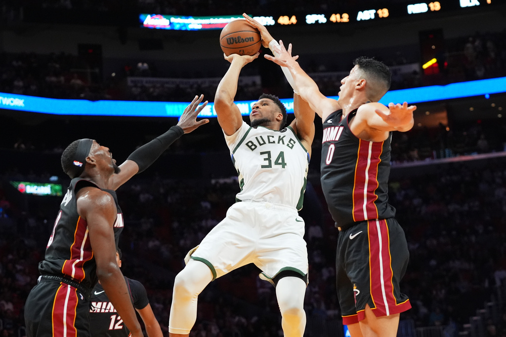 Milwaukee Bucks forward Giannis Antetokounmpo (34) aims to score as Miami Heat center Bam Adebayo (13) and Heat forward Simone Fontecchio (0) defend during the first half of an NBA basketball game Thursday, March 12, 2026, in Miami. (AP Photo/Marta Lavandier)