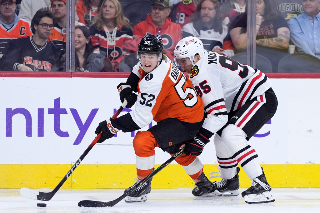 Philadelphia Flyers' Denver Barkey, left, tries to get away from Chicago Blackhawks' Ilya Mikheyev during the third period of an NHL hockey game Thursday, March 26, 2026, in Philadelphia. (AP Photo/Matt Slocum)