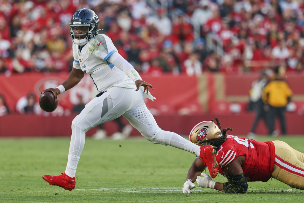 Tennessee Titans quarterback Cam Ward (1) escapes pressure from San Francisco 49ers defensive tackle Kalia Davis, right, during the second half of an NFL football game, Sunday, Dec. 14, 2025, in Santa Clara, Calif. (AP Photo/Jed Jacobsohn)