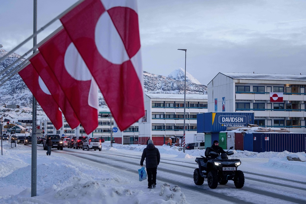 A man rides by on a quad bike past a row of Greenlandic national flags in Nuuk, Greenland, Wednesday, Jan. 14, 2026. (AP Photo/Evgeniy Maloletka)
