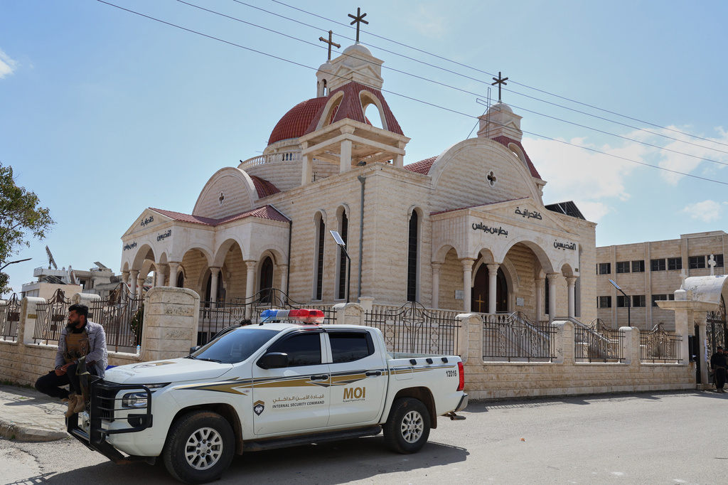 A member of Syria's Internal Security Forces sits on a vehicle parked outside a church in the predominantly Christian town of Al-Suqaylabiyah, west of Hama, Syria, Saturday, March 28, 2026, following overnight violence. (AP Photo/Omar Albam)