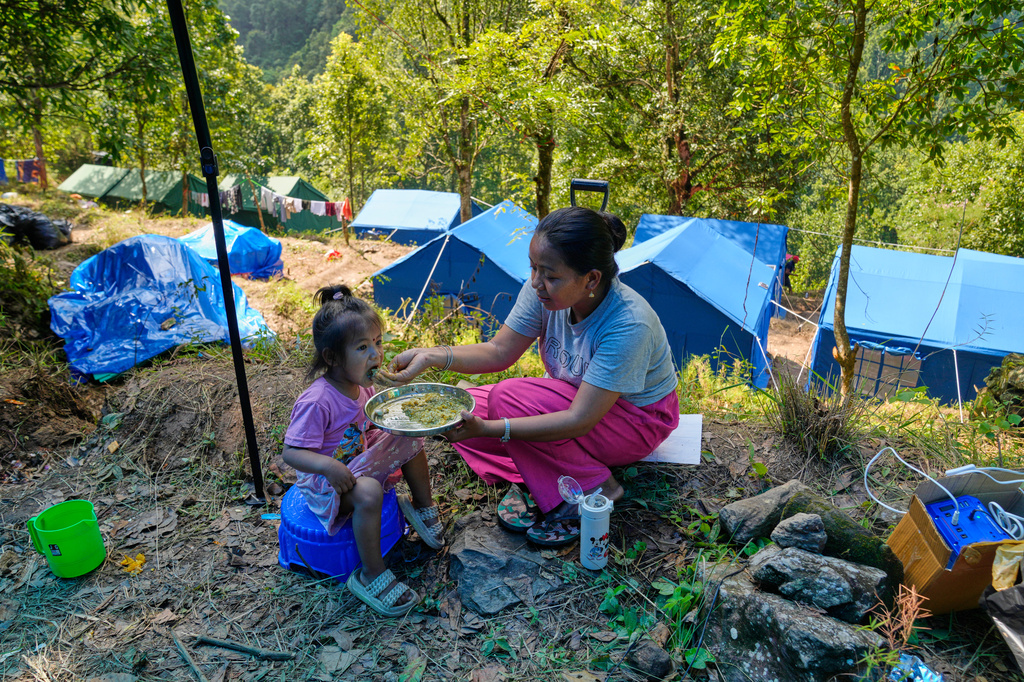 FILE - Parvati Taman, whose house was destroyed in recent flash floods, feeds her daughter Krishna Taman outside their temporary shelter on higher ground near Betrawati, Nepal, Sept. 8, 2026. (AP Photo/Dar Yasin, File)