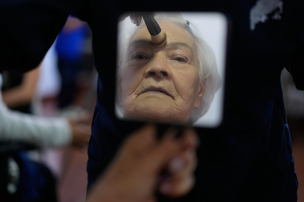 Maria Cecilia Castro, 73, has her makeup done in preparation for a quinceanera celebration for women who never had a 15th birthday party, organized by the Suenos Hechos foundation in Bogota, Colombia, Friday, Oct. 24, 2025. (AP Photo/Fernando Vergara)