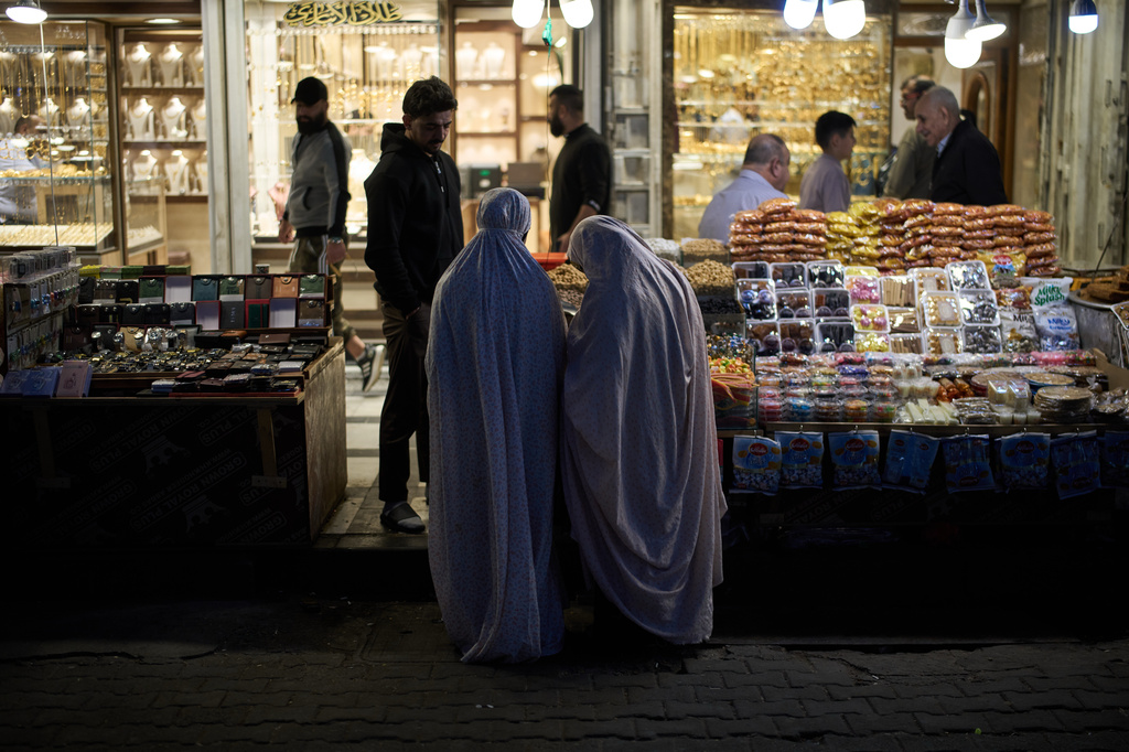 Muslim women buy goods at a market near the Kadhimiya Shrine at sunset in the Shiite neighbourhood in Baghdad, Iraq, Tuesday, March 31, 2026. (AP Photo/Leo Correa)