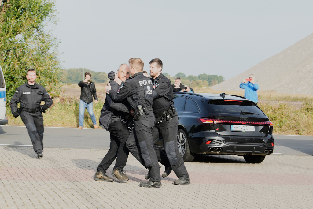 Police officers push back a British photographer who tried to take pictures inside a car leaving a prison, carrying Christian B., a suspect in the 2007 disappearance of British toddler Madeleine McCann, in Sehnde, Germany, Wednesday, Sept. 17, 2025. (AP Photo/Markus Schreiber)