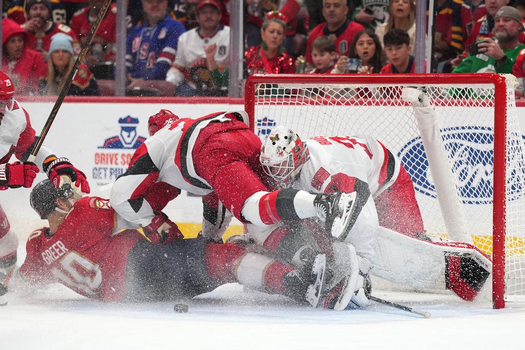 Florida Panthers left wing A.J. Greer and Carolina Hurricanes defenseman Sean Walker collide into goaltender Brandon Bussi during the second period of an NHL hockey game, Friday, Dec. 19, 2025, in Sunrise, Fla. (AP Photo/Jim Rassol)