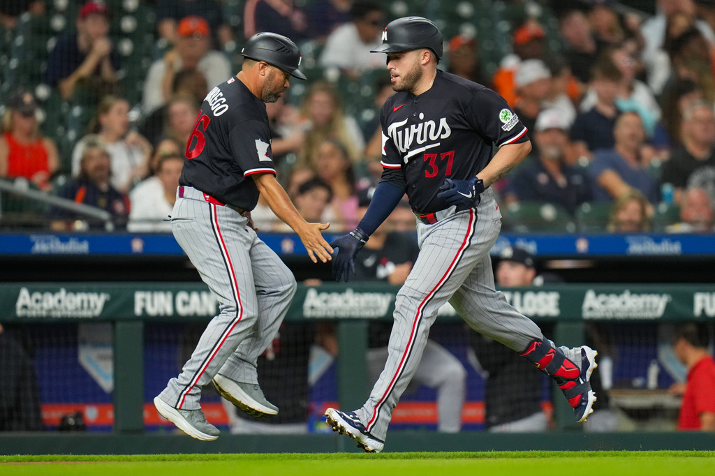 Minnesota Twins' Victor Caratini (37) greets third base coach Ramon Borrego, left, while rounding the bases on his solo home run during the fourth inning of a baseball game in Houston, Monday, June 29, 2026. (AP Photo/Jon Shapley)