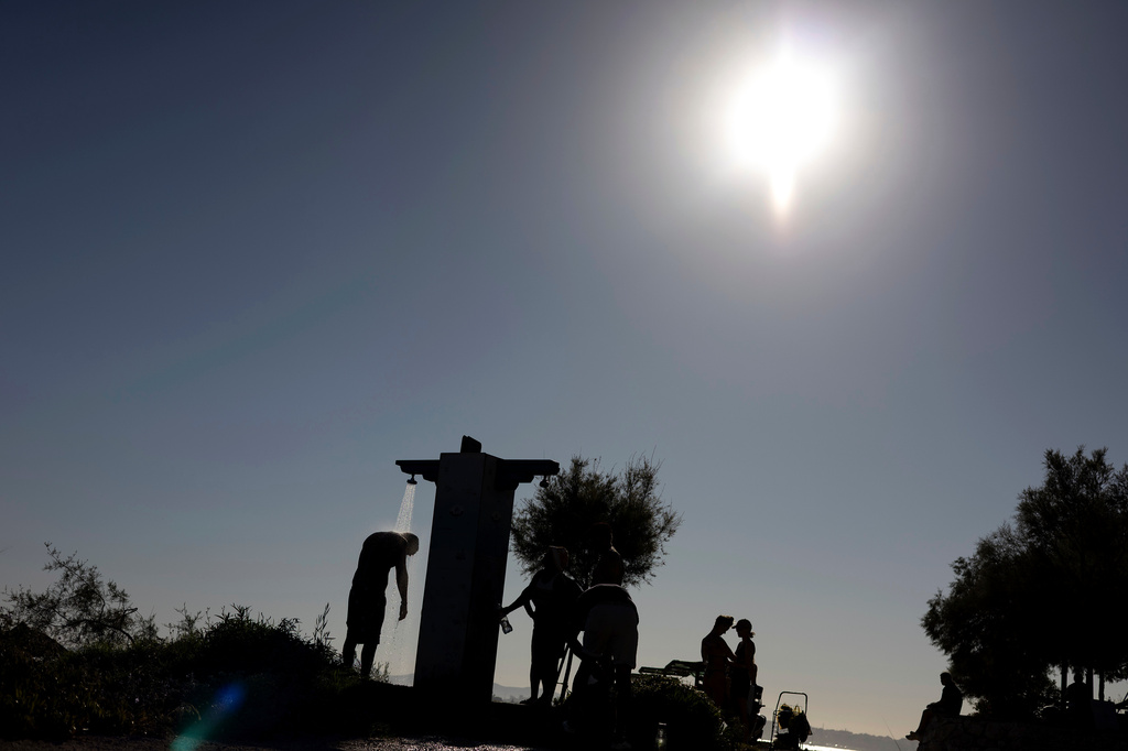 FILE - A man takes a shower near a beach during a hot day in Palaio Faliro suburb, south of Athens, Greece, July 6, 2025. (AP Photo/Yorgos Karahalis, File)