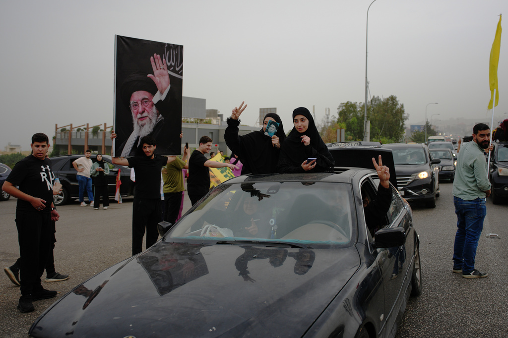 Displaced residents hold portraits of late Iran's Supreme Leader Ayatollah Ali Khamenei, left, and late Hezbollah leader Hassan Nasrallah as they drive back to their villages, in Jiyeh, near Saida, southern Lebanon, Friday, April 17, 2026, following a ceasefire between Israel and Hezbollah. (AP Photo/Hassan Ammar)