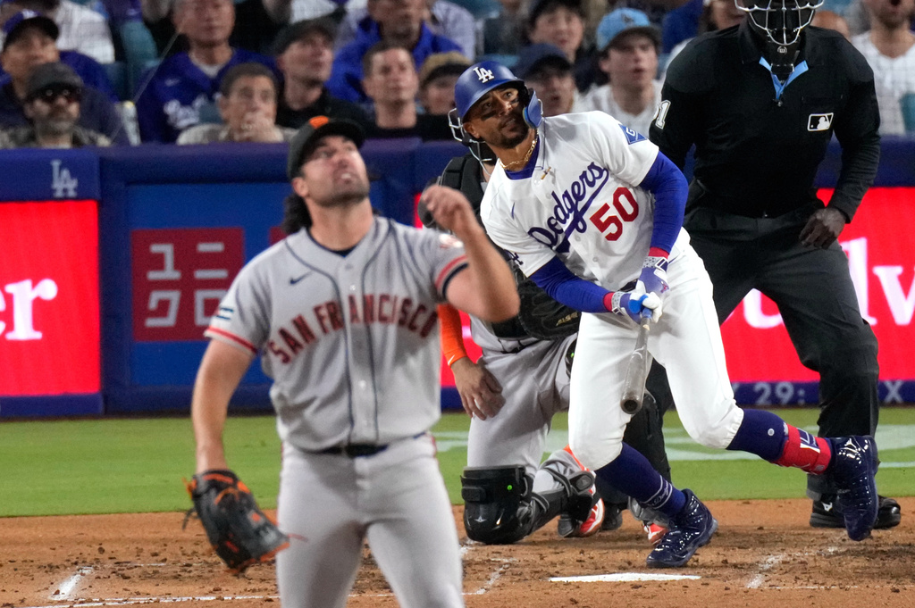 Los Angeles Dodgers' Mookie Betts, right, hits a solo home run as San Francisco Giants pitcher Robbie Ray, left, and catcher Jesus Rodriguez watch during the third inning of a baseball game Wednesday, May 13, 2026, in Los Angeles. (AP Photo/Mark J. Terrill)