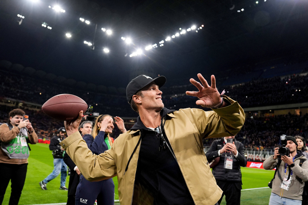 Former NFL football player Tom Brady, left, throws a football before the Serie A soccer match between AC Milan and Como, Wednesday, Feb. 18 2026, in Milan, Italy. (Fabio Ferrari/LaPresse via AP)