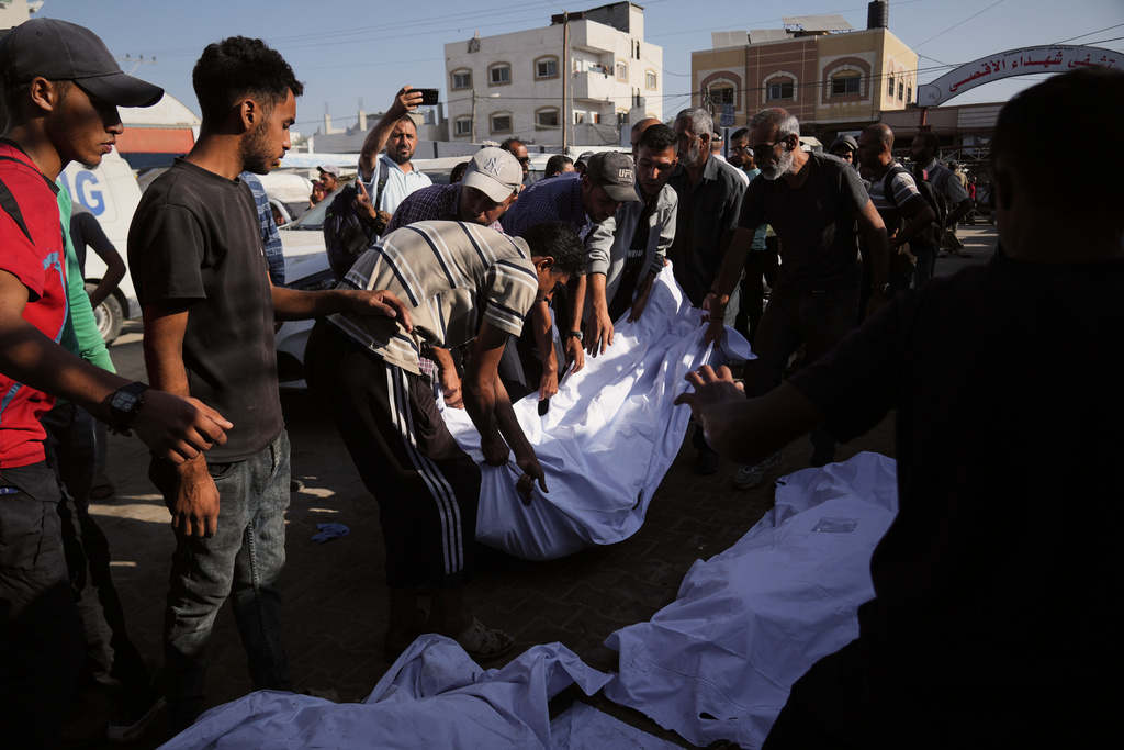Palestinians carry the body of their relative killed in an Israeli military strike as they gather outside Al-Aqsa Hospital in Deir al-Balah, in the central Gaza Strip, Tuesday, Sept. 30, 2025. (AP Photo/Abdel Kareem Hana)