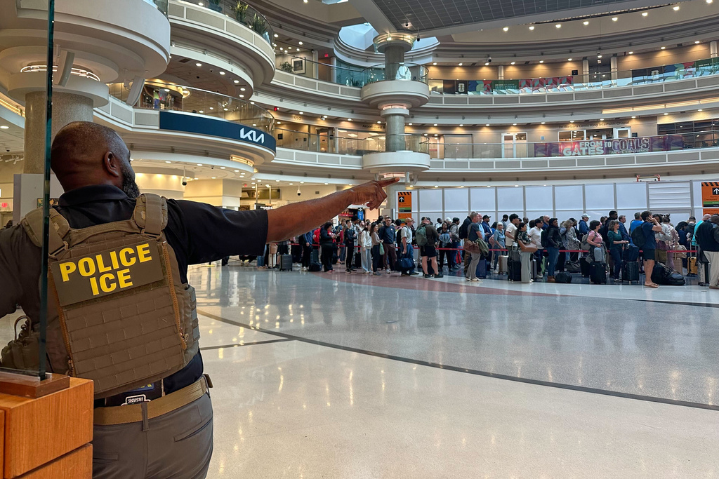 A federal immigration agent is seen as people wait in a TSA line at the Hartsfield-Jackson Atlanta International Airport, Monday, March 23, 2026, in Atlanta. (AP Photo/Emilie Megnien)