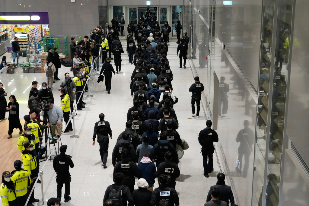 South Koreans, walking in the line at center, who are allegedly involved in online scams in Cambodia, arrive at the Incheon International Airport in Incheon, South Korea, Friday, Jan. 23, 2026. (AP Photo/Ahn Young-joon)