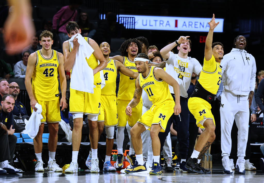 Michigan bench celebrates a slam dunk by teammate Oscar Goodman (5), not pictured, during the second half of an NCAA college basketball game against Auburn Tuesday, Nov. 25, 2025, in Las Vegas. (AP Photo/Ronda Churchill)