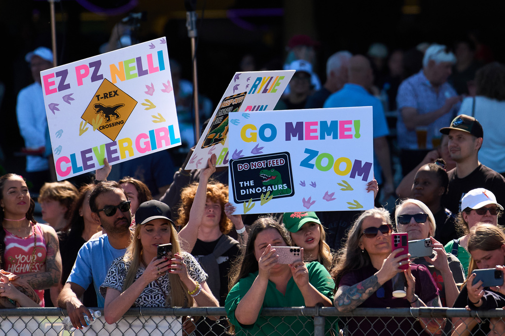 People wave signs for their favorite racers during the T-Rex World Championship Races at Emerald Downs, Sunday, July 12, 2026, in Auburn, Wash. (AP Photo/Lindsey Wasson)