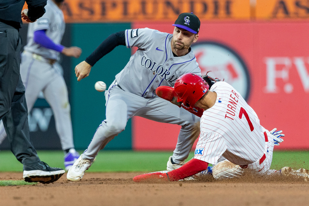 Philadelphia Phillies' Trea Turner (7) slides into second as Colorado Rockies second baseman Edouard Julien, second from right, waits for the ball to tag him out in the fourth inning of a baseball game, Saturday, May 9, 2026, in Philadelphia. (AP Photo/Laurence Kesterson)