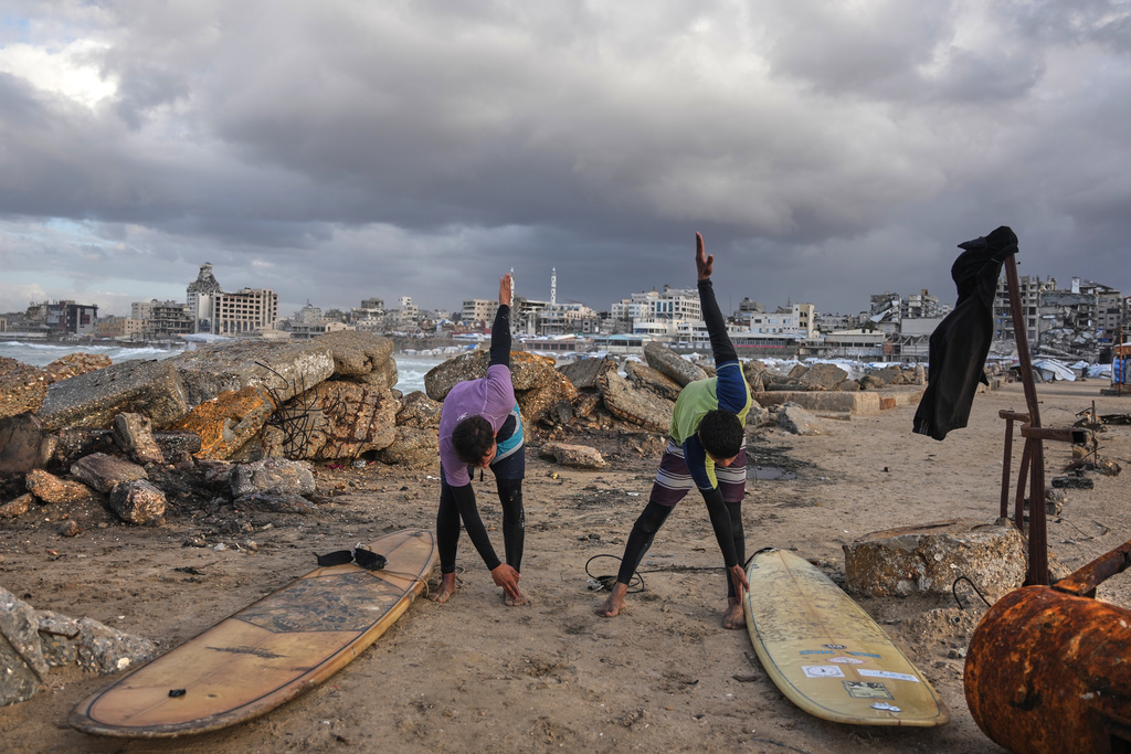 Palestinian Khalil Abu Jayyab, right, and Tahseen Abu Assi warm up before surfing on the beach in Gaza City, Sunday, Dec. 28, 2025. (AP Photo/Jehad Alshrafi)