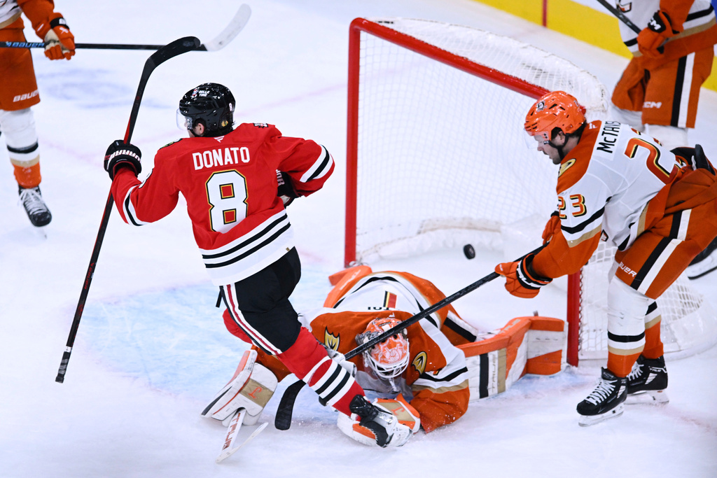 Chicago Blackhawks' Ryan Donato (8) scores the winning goal against Anaheim Ducks goalie Lukas Dostal, center, and Mason McTavish (23) in overtime of an NHL hockey game Sunday, Oct. 19, 2025, in Chicago. (AP Photo/Paul Beaty)