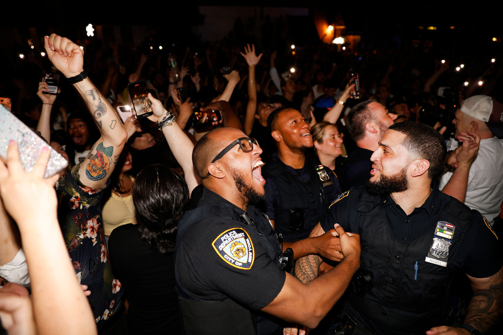 New York City police officers join fans and celebrate the Knicks victory after a watch party for Game 5 of the NBA Finals basketball series against the San Antonio Spurs, Saturday, June 13, 2026, in New York. (AP Photo/Stefan Jeremiah)