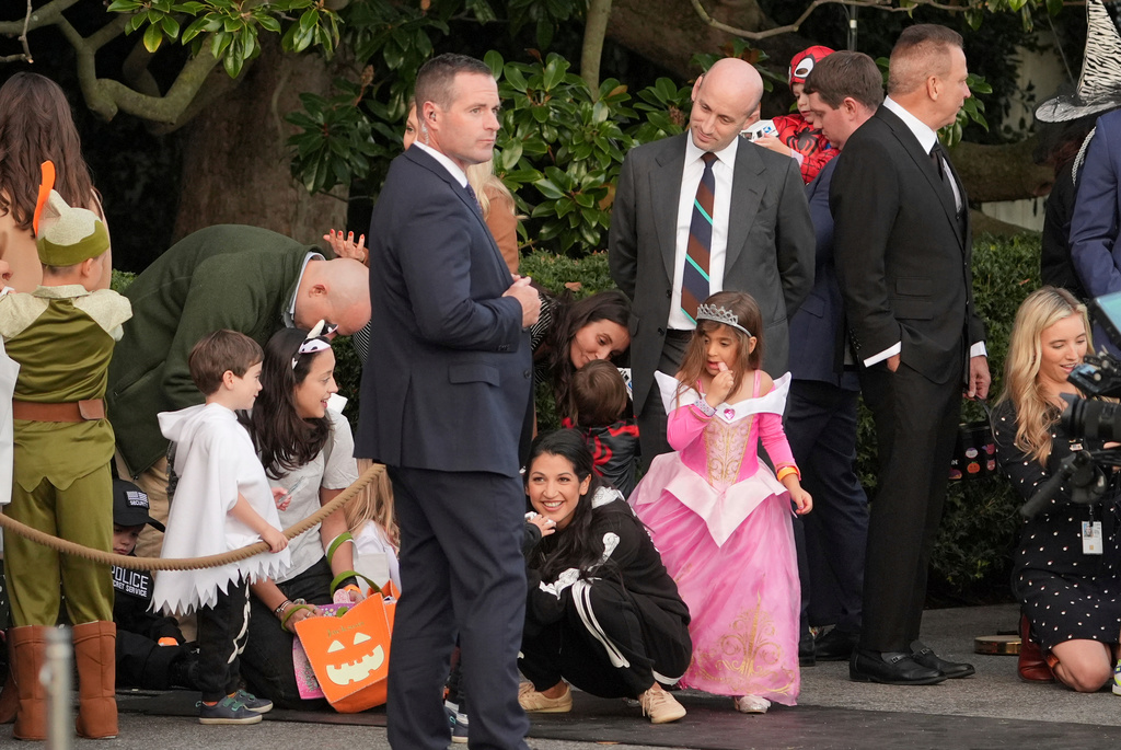 Stephen Miller, White House deputy chief of staff, fourth from right, and his wife Katie Miller, seated center, attend a Halloween event before President Donald Trump and first lady Melania Trump arrive to greet families during a Halloween event on the South Lawn of the White House, Thursday, Oct. 30, 2025, in Washington. (AP Photo/Jacquelyn Martin)