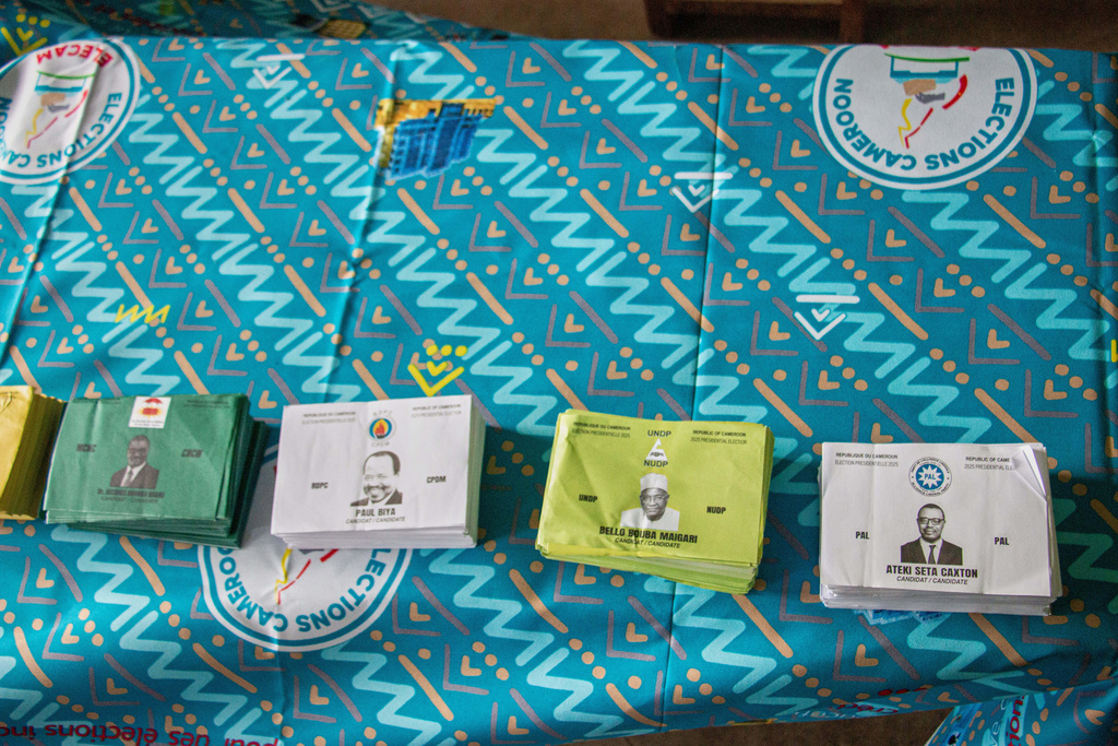 Stacks of ballot papers bearing the faces of presidential candidates are displayed on a table at a polling station before voting begins in Garoua, Cameroon, Sunday, Oct. 12, 2025.(AP Photo/Welba Yamo Pascal)
