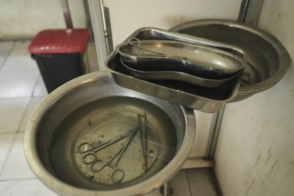 Surgical scissors and scalpels lye in fly-infested water at a government hospital in Konduga, in northeast Nigeria's Borno state, Wednesday, July 23, 2025. (AP Photo/Sunday Alamba)