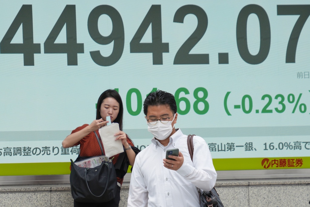 People stand in front of an electronic stock board showing Japan's Nikkei 225 index at a securities firm Tuesday, Sept. 30, 2025, in Tokyo. (AP Photo/Eugene Hoshiko)