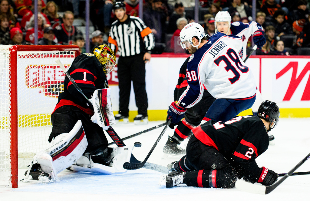 Columbus Blue Jackets' Boone Jenner (38) attempts to deflect a shot past Ottawa Senators' goaltender Leevi Merilainen (1) during the first period of an NHL hockey game, in Ottawa, Ontario, Monday, Dec. 29, 2025. (Spencer Colby/The Canadian Press via AP)