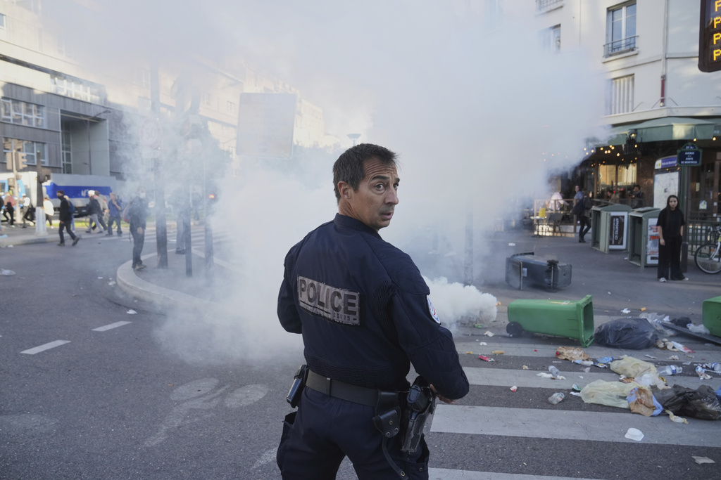 A police officer stands next to bins placed on a street to block it during the "Bloquons Tout" (Block Everything) protest movement in Paris, Wednesday, Sept. 10, 2025. (AP Photo/Thibault Camus)