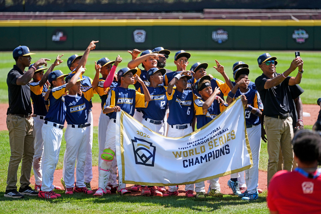 Curacao players and coaches pose for a group selfie with the International Championship banner after defeating Japan in the International Championship baseball game at the Little League World Series tournament in South Williamsport, Pa., Saturday, Aug. 29, 2026. (AP Photo/Gene J. Puskar)