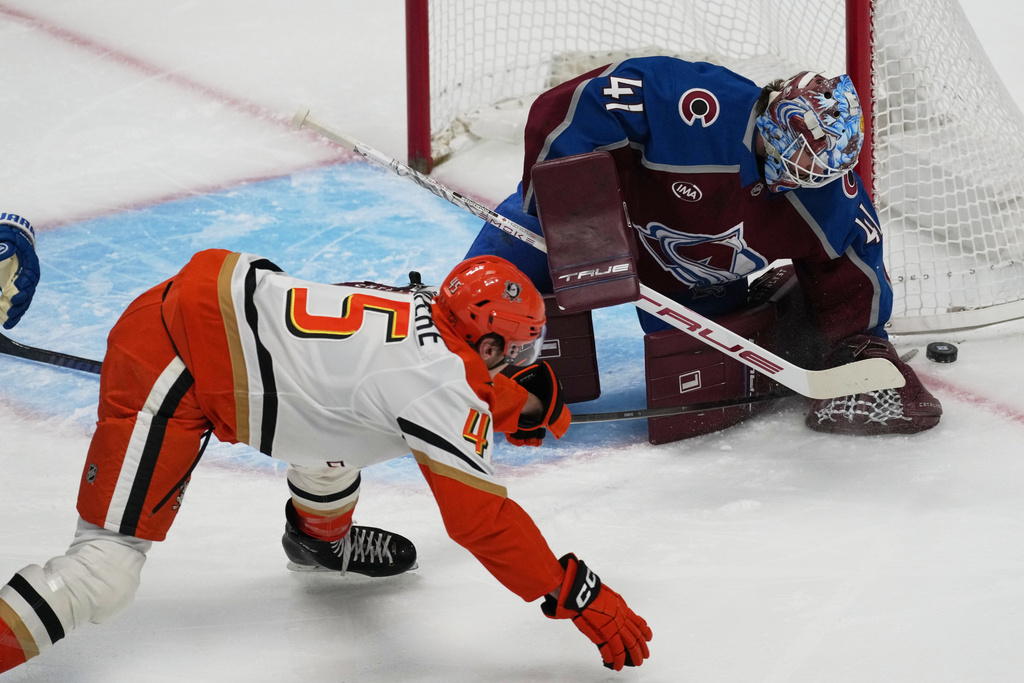 Colorado Avalanche goaltender Scott Wedgewood, back, stops a shot from Anaheim Ducks right wing Beckett Sennecke in the first period of an NHL hockey game, Wednesday, Jan. 21, 2026, in Denver. (AP Photo/David Zalubowski)