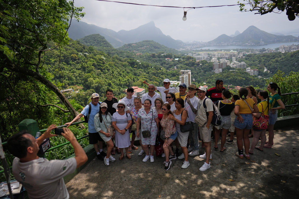 A tour guide takes a photo of tourists at a viewpoint in the Rocinha favela, as Rio de Janeiro recorded a record number of international tourists in 2025, Tuesday, Jan. 27, 2026. (AP Photo/Silvia Izquierdo)