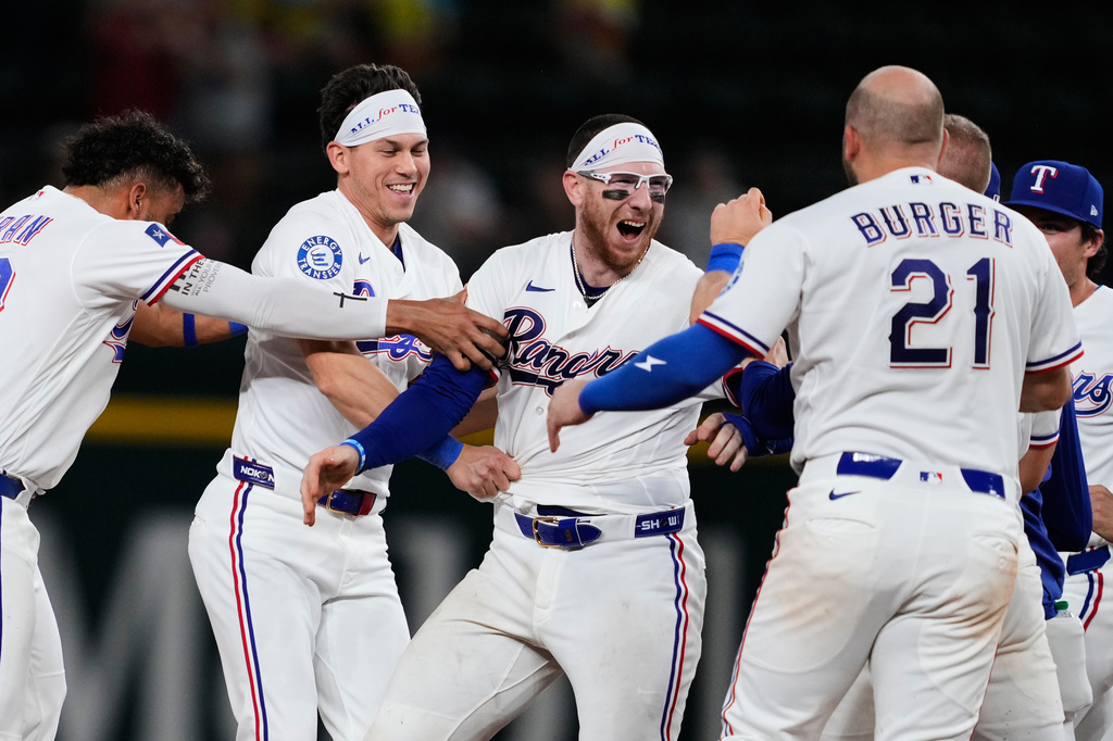 Texas Rangers' Ezequiel Duran, from left, Sam Haggerty, Danny Jansen and Jake Burger (21), celebrate Jansen's run-scoring single in the ninth inning of a baseball game against the Arizona Diamondbacks Wednesday, May 13, 2026, in Arlington, Texas. (AP Photo/Tony Gutierrez)