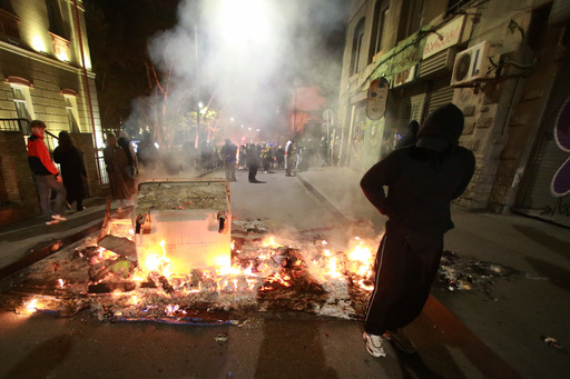 A demonstrator stands behind a burning barricade not far from a police line during an opposition rally in the city center of Tbilisi, Georgia, on Sunday, Oct. 5, 2025, boycotting the municipal elections and calling for the release of political opponents. (AP Photo/Zurab Tsertsvadze) A demonstrator stands behind a burning barricade not far from a police line during an opposition rally in the city center of Tbilisi, Georgia, on Sunday, Oct. 5, 2025, boycotting the municipal elections and calling for the release of political opponents. (AP Photo/Zurab Tsertsvadze)