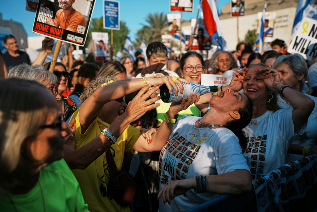 People react as they gather to watch a live broadcast of Israeli hostages released from Gaza at a plaza known as hostages square in Tel Aviv, Israel, Monday, Oct. 13, 2025. The release took place as part of a cease-fire agreement between Israel and Hamas. (AP Photo/Emilio Morenatti)