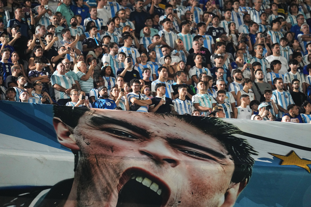 Fans wait for the start of a friendly soccer match between Argentina and Zambia next to a banner of Argentine soccer legend Diego Maradona in Buenos Aires, Argentina, Tuesday, March 31, 2026. (AP Photo/Rodrigo Abd)