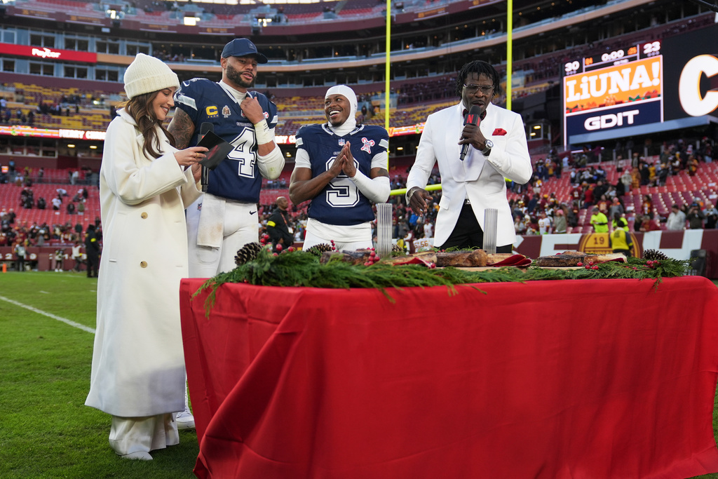 Dallas Cowboys quarterback Dak Prescott (4) and wide receiver Kavontae Turpin (9) are interview by Kay Adams, left, and Michael Irvin, right, following an NFL football game against the Washington Commanders Thursday, Dec. 25, 2025, in Landover, Md. (AP Photo/Stephanie Scarbrough)