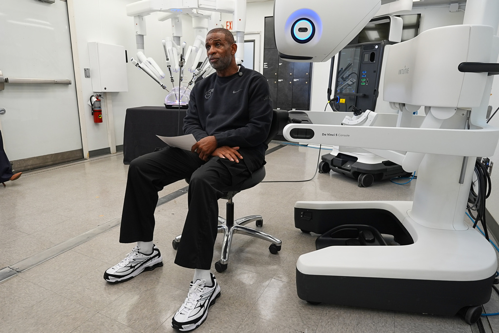 Colorado head football coach Deion Sanders talks after working the Da Vinci robotic surgical machine used to remove his cancerous bladder last year after a demonstration of the device Tuesday, June 23, 2026, in Boulder, Colo. (AP Photo/David Zalubowski)