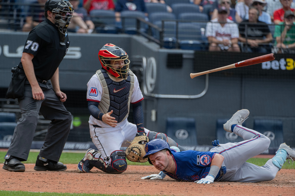 New York Mets' A.J. Ewing hits the deck after dodging an inside pitch from Cleveland Guardians relief pitcher Slade Cecconi as catcher Patrick Bailey and umpire umpire John Bacon look on during the eighth inning of a baseball game, Thursday, Aug. 6, 2026, in Cleveland. (AP Photo/Phil Long)