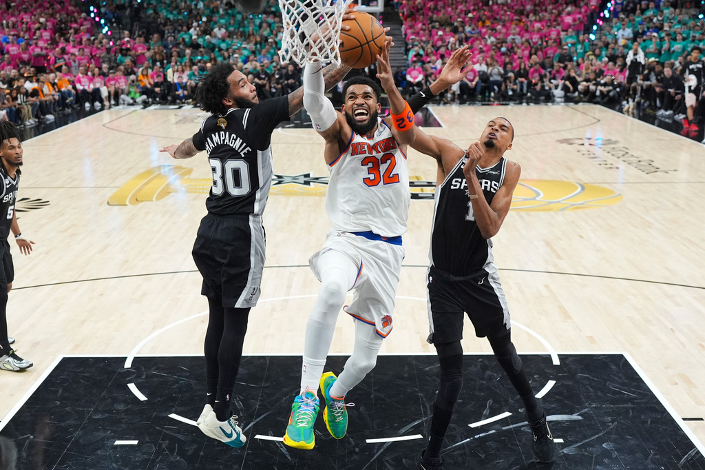 New York Knicks center Karl-Anthony Towns (32) shoots between San Antonio Spurs forward Victor Wembanyama (1) and forward Julian Champagnie (30) during the first half of Game 1 of the NBA Finals basketball series, Wednesday, June 3, 2026, in San Antonio. (AP Photo/Eric Gay)