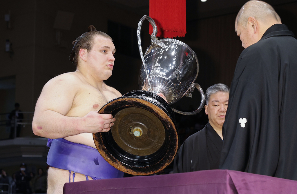 Ukrainian Aonishiki, left, receives the championship trophy after winning the Kyushu Grand Sumo Tournament in Fukuoka, western Japan, Sunday, Nov. 23, 2025. (Kyodo News via AP)