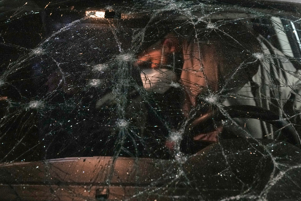 A man inspects a car damaged in an Israeli airstrike at the Ramlet al-Baida public beach in Beirut, Lebanon, early Thursday, March 12, 2026. (AP Photo/Bilal Hussein)