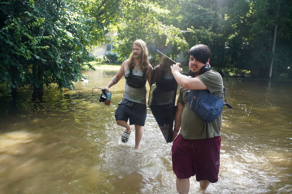Darius Canler and Curtis Carey carry a TV from their flooded home in Indianapolis, Sunday, Aug. 16, 2026. (AP Photo/Obed Lamy)